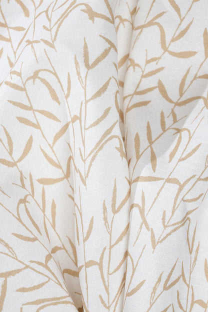 Luxury botanical fabric in warm brass tones with layered painterly organic design, ideal for upholstery, drapery, and sophisticated contemporary interiors.